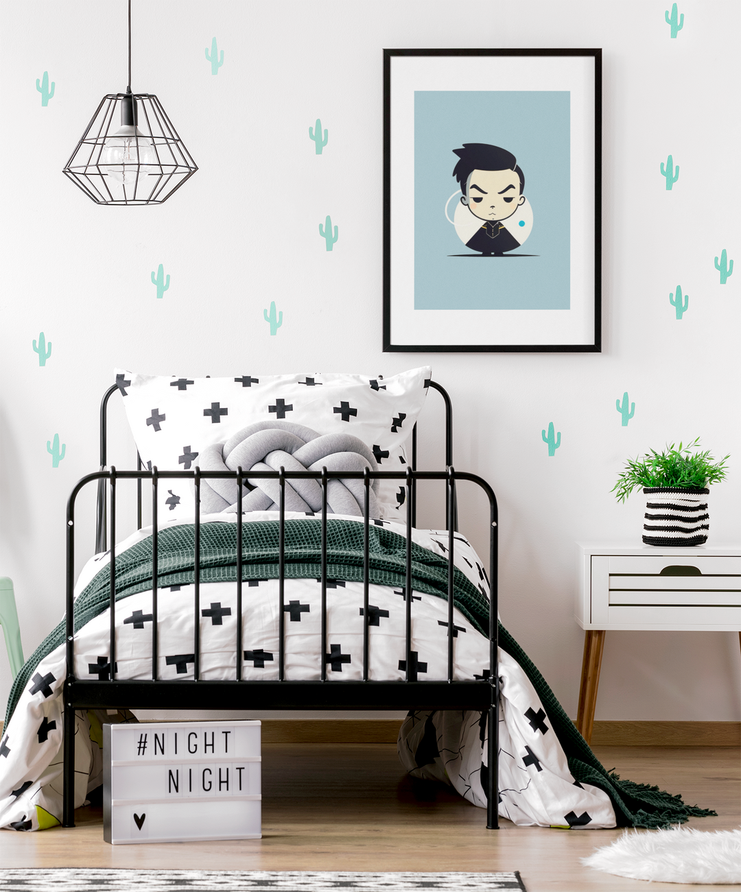Children's bedroom with black metal bed, framed artwork, and cactus wall decals.