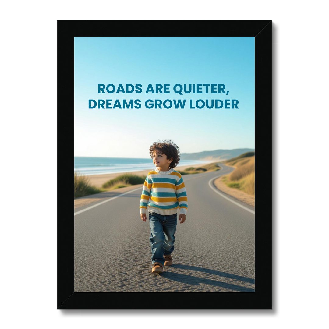 Framed poster with a child walking on a road by the sea and the quote 'Roads are quieter, dreams grow louder'.
