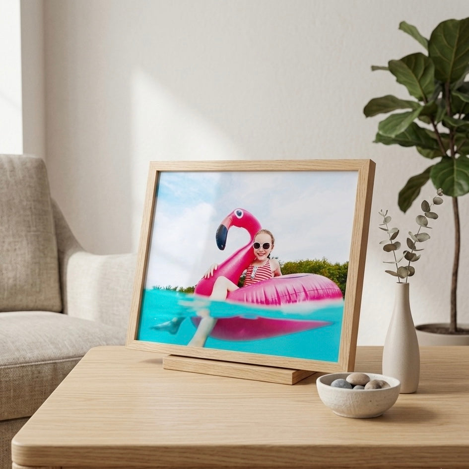 Framed photo tile of a child on an inflatable flamingo pool float in a living room setting. by printlagoon