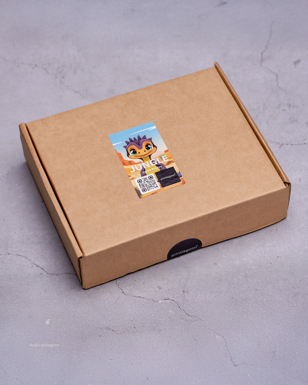 Kraft paper box with a colorful sticker featuring a cartoon character on a gray surface by printlagoon