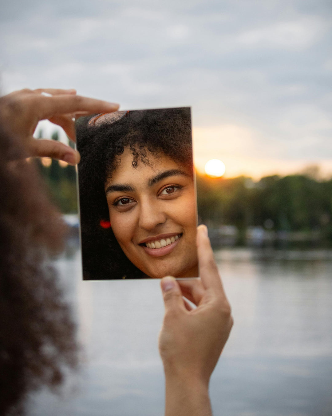Person holding a photo of a smiling person against a sunset over water background. printed on acrylic, online sell by printlagoon.